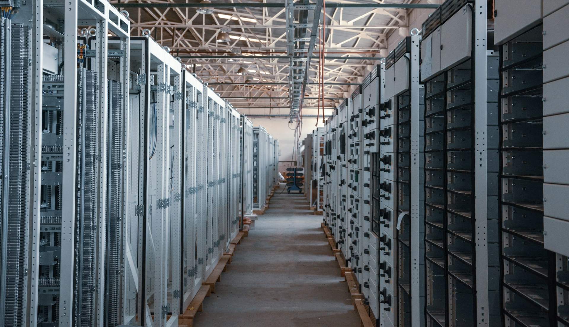 Aisle of newly installed equipment racks in an unfinished hall